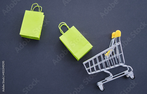 mini shopping cart, eco-friendly paper bag for shopping in hypermarkets on a black background.