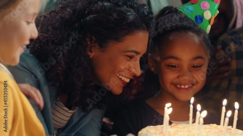 happy birthday girl blowing candles on cake making wish celebrating party with family and friends children having fun celebration at home 4k footage photo