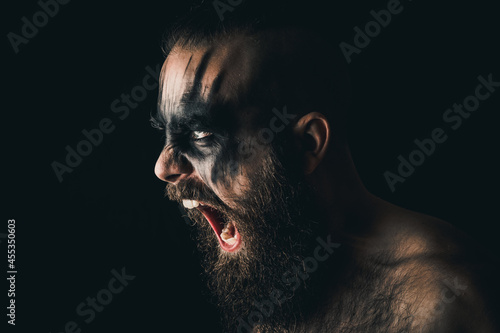 Fotografiet Portrait of a Viking warrior with black war paint, screaming with rage and anger