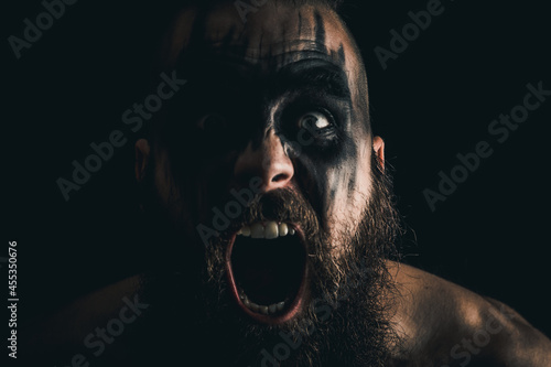Portrait of a Viking warrior with black war paint, screaming with rage and anger photo