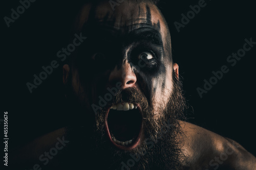 Portrait of a Viking warrior with black war paint, screaming with rage and anger