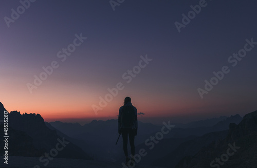Silhouette einer jungen Frau vor einer Gebirgskette  zu Sonnenaufgang