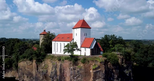 Church (13th century, 1848) on a mountain spur, surrounded by a lake or flooded quarry. Aerial view footage.