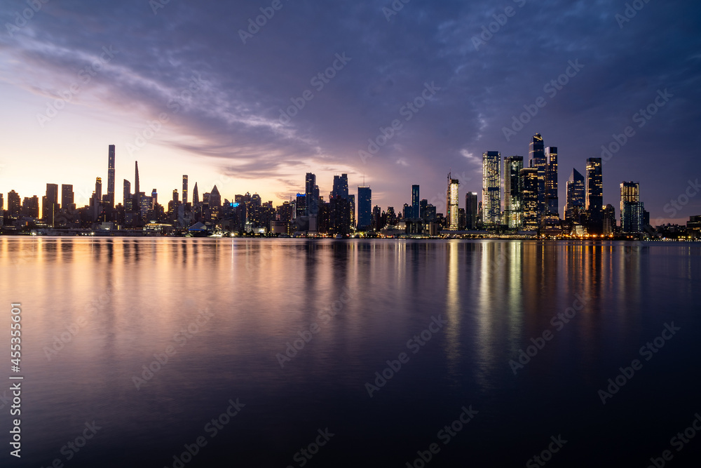 New York, NY - USA - Horizontal image of the skyline of the westside of Manhattan at sunrise, with reflections seen in the Hudson River.