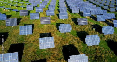 Aerial view of solar energy modules on a meadow. Photovoltaic panels casting shadows in twilight. 