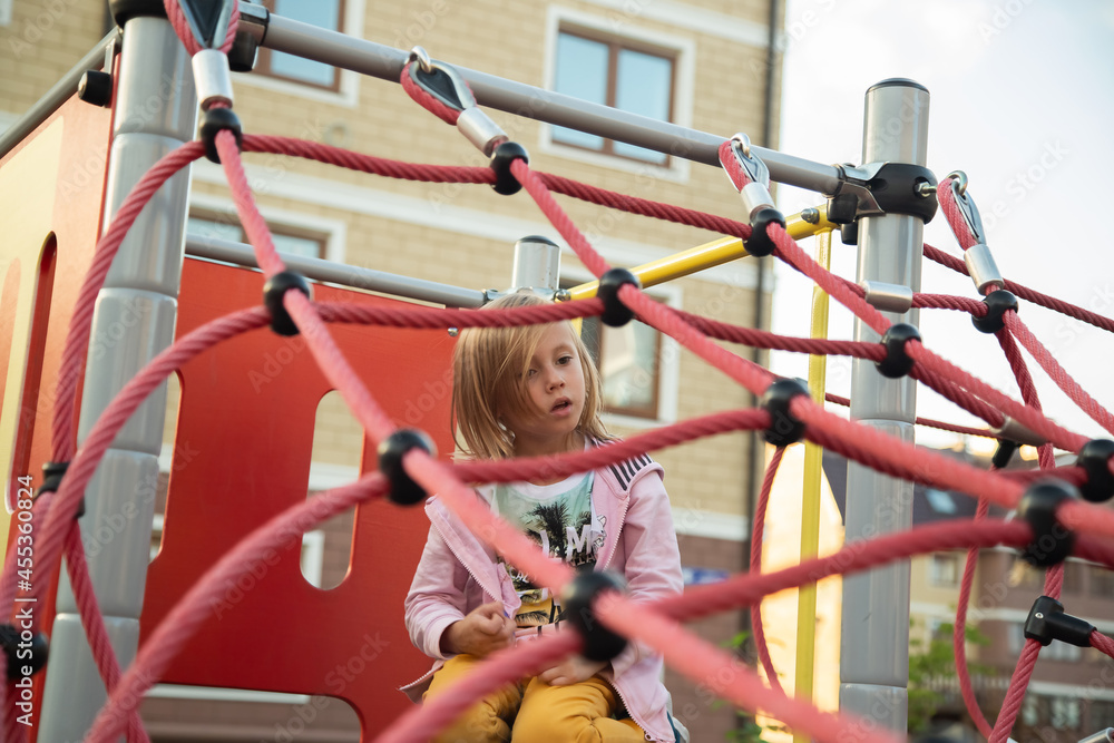 The little girl climbs ropes at the playground