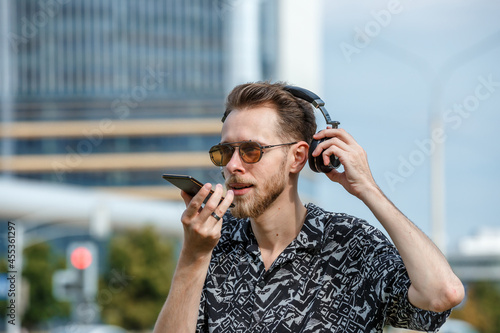 A young man wearing headphones and sunglasses listens to music © Superzoom