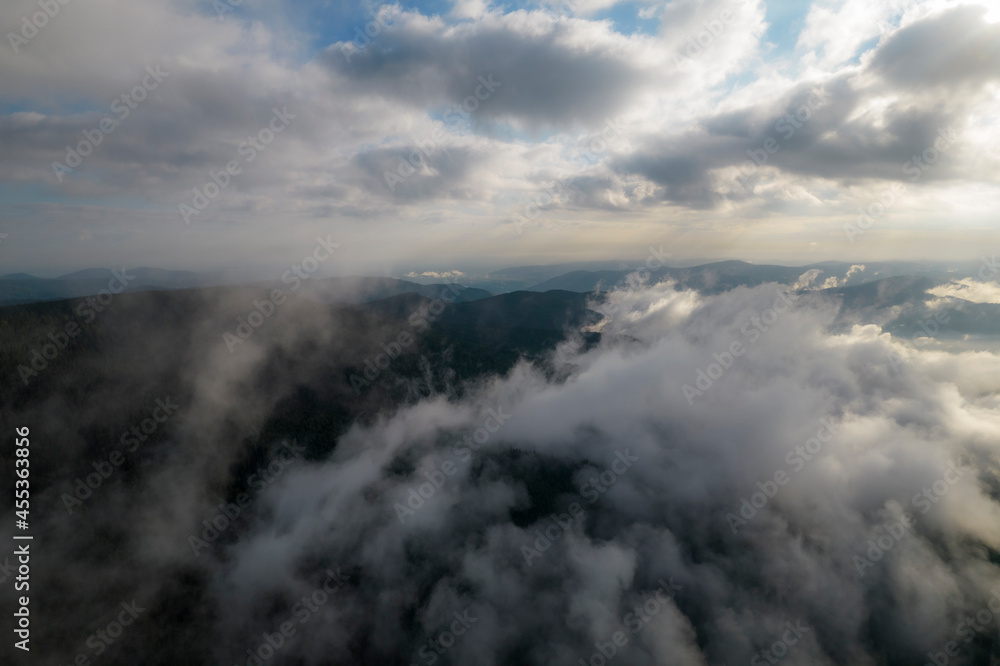 Flying over the clouds during morning sunrise in Carpathian Mountains. Above.Golden fluffy clouds moving softly on the sky and the sun shining through the clouds with beautiful rays and lens flare.