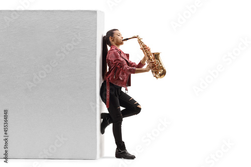 Photography Full length profile shot of a young female saxophonist playing against a wall