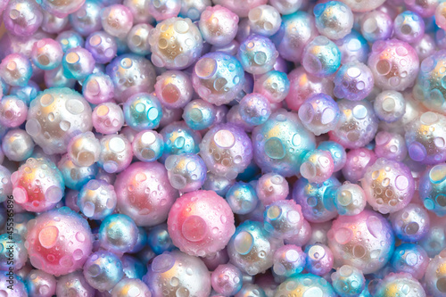 Beautiful background with pearl pearls, top view. Abstract texture for festive backgrounds. Shiny surface of Christmas decorations. Gems close-up. Multicolored bright background. © Vera