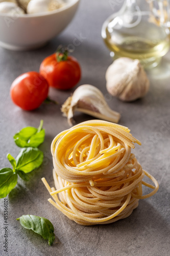 Italian pasta nest, basil, garlic and tomato. Uncooked spaghetti nest