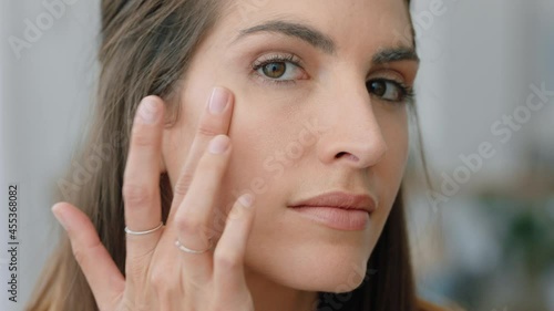 portrait attractive young woman looking in mirror at perfect healthy skin touching face with hands enjoying smooth natural complexion with anti aging skincare getting ready at home beauty concept