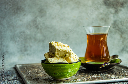 Cup of traditional Turkish sweet tea with a bowl of pistachio halva on a metal tray photo