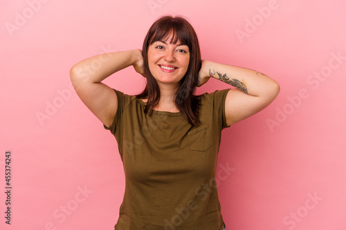 Young curvy caucasian woman isolated on pink background feeling confident, with hands behind the head.