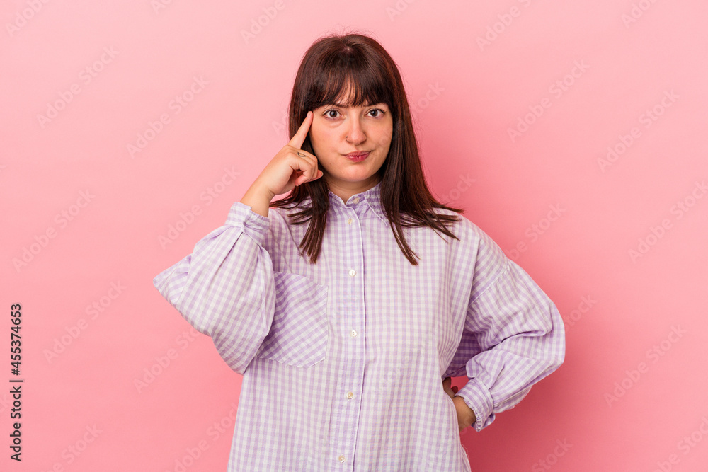 Young curvy caucasian woman isolated on pink background pointing temple with finger, thinking, focused on a task. Young curvy caucasian woman isolated on pink background pointing temple with finger, thinking, focused on a task.