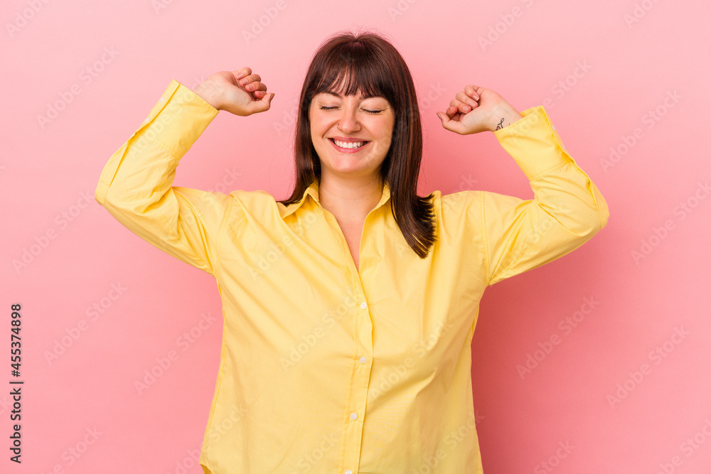 Young curvy caucasian woman isolated on pink background celebrating a special day, jumps and raise arms with energy. Young curvy caucasian woman isolated on pink background celebrating a special day, jumps and raise arms with energy.