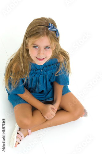 Charming little girl sitting on floor in studio