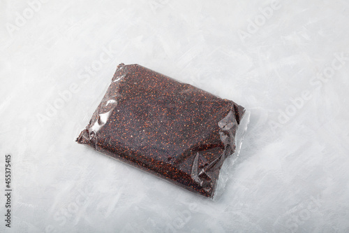 Organic ragi or black quinoa in a transparent package. Gray background, selective focus, copy space. Cereals contain a large amount of protein, antioxidants, dietary fiber, vitamins and minerals photo