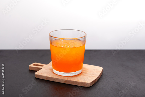 Crushed ice with orange juice or syrup beverage. Orange granizado in glass. Dark background, selective focus, copy space