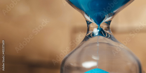 banner Sand running through the bulbs of an hourglass measuring the passing time in a countdown to a deadline, on a dark background with copy space. photo