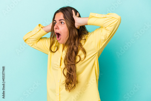 Young caucasian woman isolated on blue background screaming, very excited, passionate, satisfied with something.