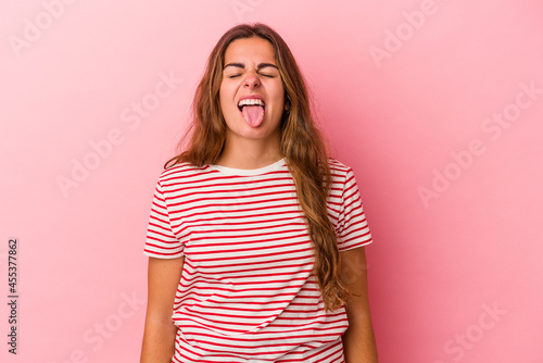 Young caucasian woman isolated on pink background  funny and friendly sticking out tongue.