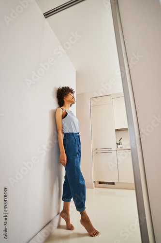 Принти на полотні Barefoot woman daydreaming leaned back against the wall