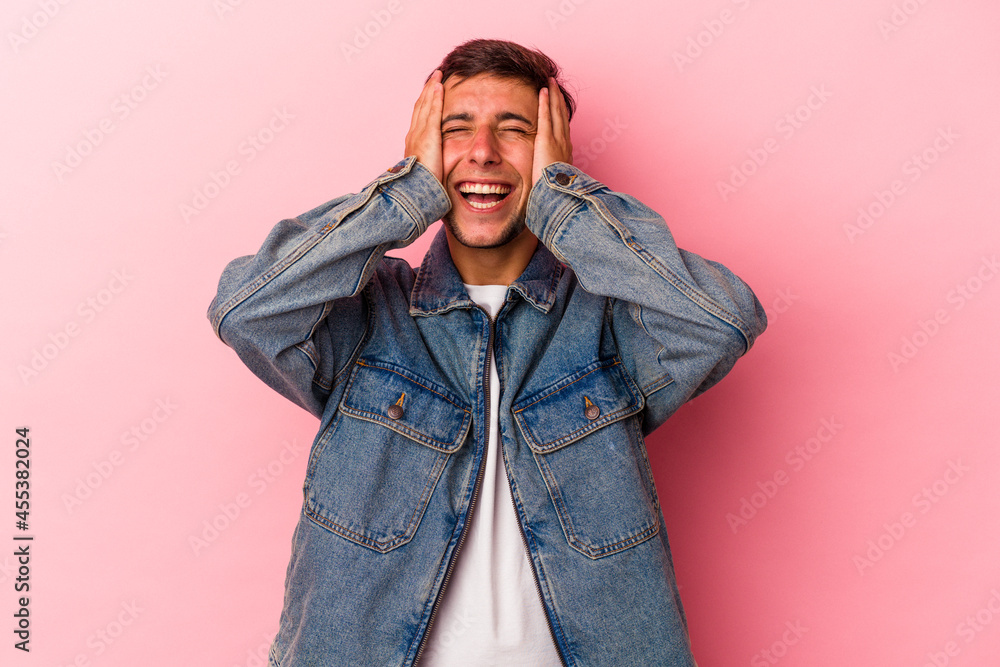 Fototapeta premium Young caucasian man with tattoos isolated on yellow background laughs joyfully keeping hands on head. Happiness concept.