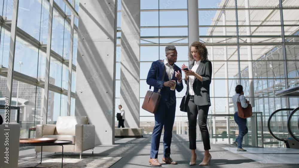 business people chatting african american businessman talking to female colleague using smartphone discussing work having conversation in corporate office 4k business people chatting african american businessman talking to female colleague using smartphone discussing work having conversation in corporate office 4k