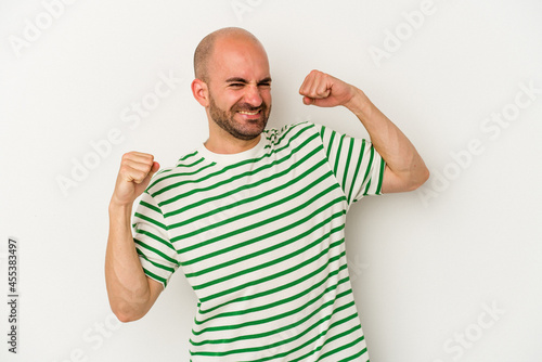 Young bald man isolated on white background celebrating a special day, jumps and raise arms with energy.