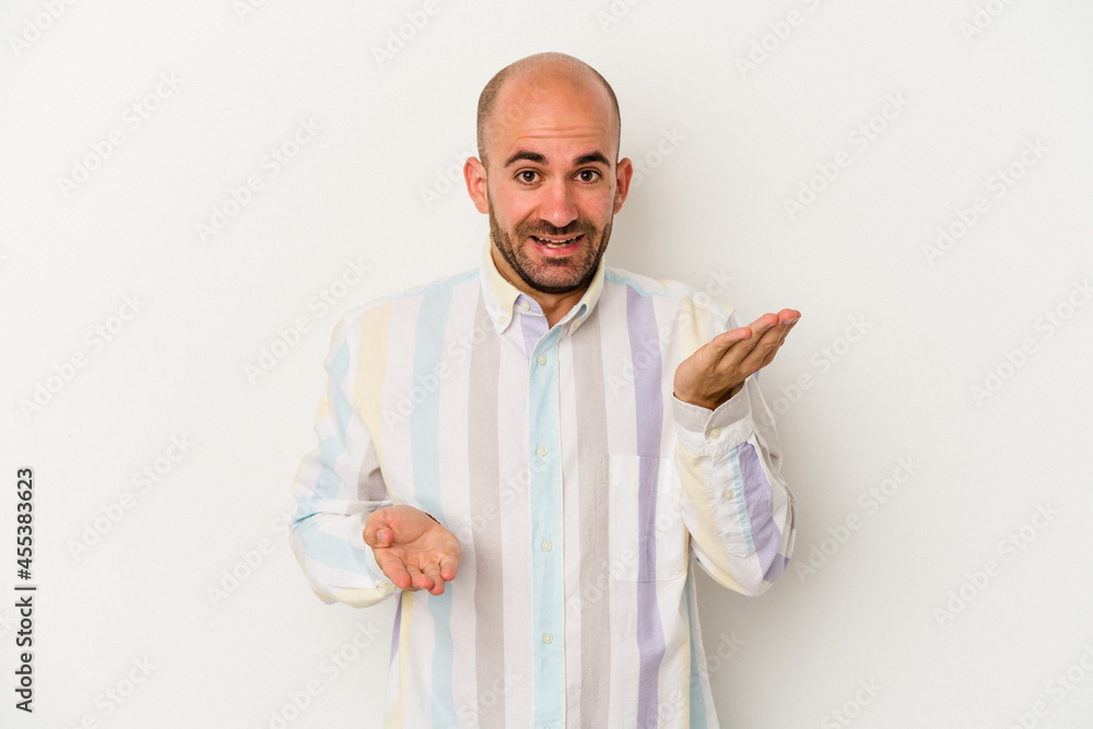Young bald man isolated on white background makes scale with arms, feels happy and confident. Young bald man isolated on white background makes scale with arms, feels happy and confident.