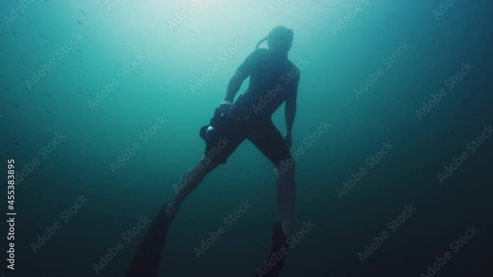 Underwater photographer. Man in wetsuit slowly ascends with underwater camera in the lake Underwater photographer. Man in wetsuit slowly ascends with underwater camera in the lake