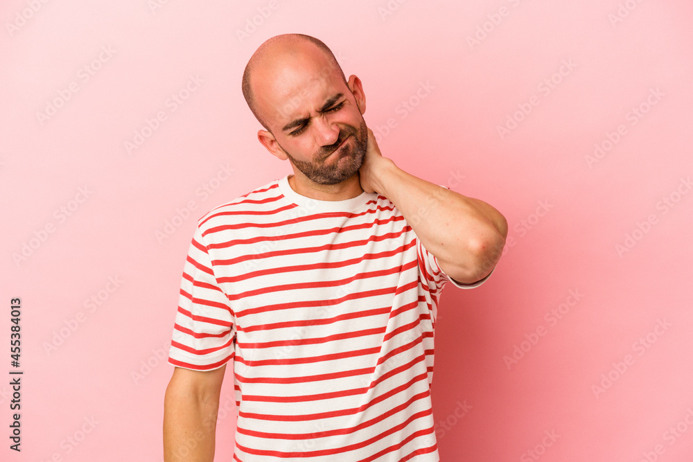 Young caucasian bald man isolated on pink background having a neck pain due to stress, massaging and touching it with hand. Young caucasian bald man isolated on pink background having a neck pain due to stress, massaging and touching it with hand.