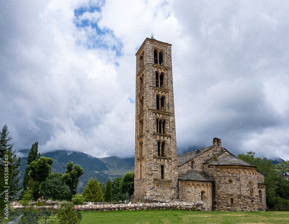 Romanesque church of San Clemente de Tahull, with its high bell tower and the mountains of the Lleida Pyrenees in the background on a cloudy day