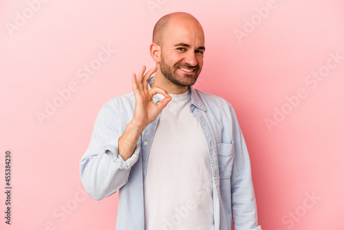 Young caucasian bald man isolated on pink background cheerful and confident showing ok gesture.