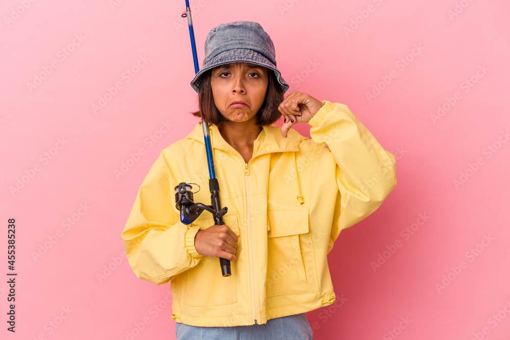 Young mixed race woman practicing fishing isolated on pink background showing a dislike gesture, thumbs down. Disagreement concept. Young mixed race woman practicing fishing isolated on pink background showing a dislike gesture, thumbs down. Disagreement concept.
