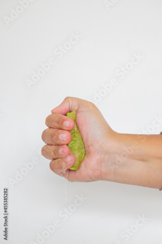 Hand squeeze lime with lime drop on a white background
