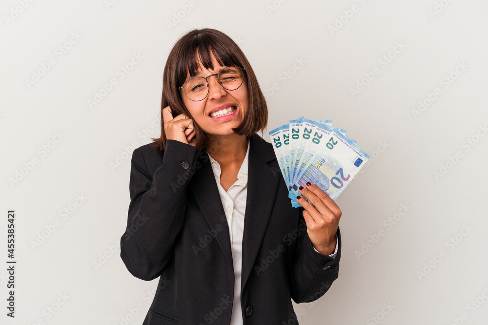 Young mixed race business woman holding a banknotes isolated on white background covering ears with hands. Young mixed race business woman holding a banknotes isolated on white background covering ears with hands.