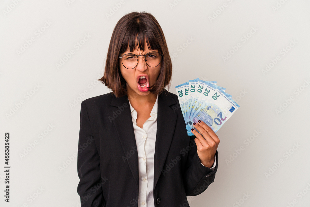 Young mixed race business woman holding a banknotes isolated on white background screaming very angry and aggressive. Young mixed race business woman holding a banknotes isolated on white background screaming very angry and aggressive.