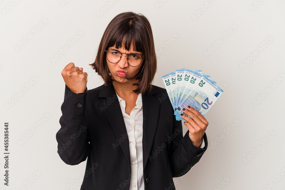 Young mixed race business woman holding a banknotes isolated on white background showing fist to camera, aggressive facial expression. Young mixed race business woman holding a banknotes isolated on white background showing fist to camera, aggressive facial expression.