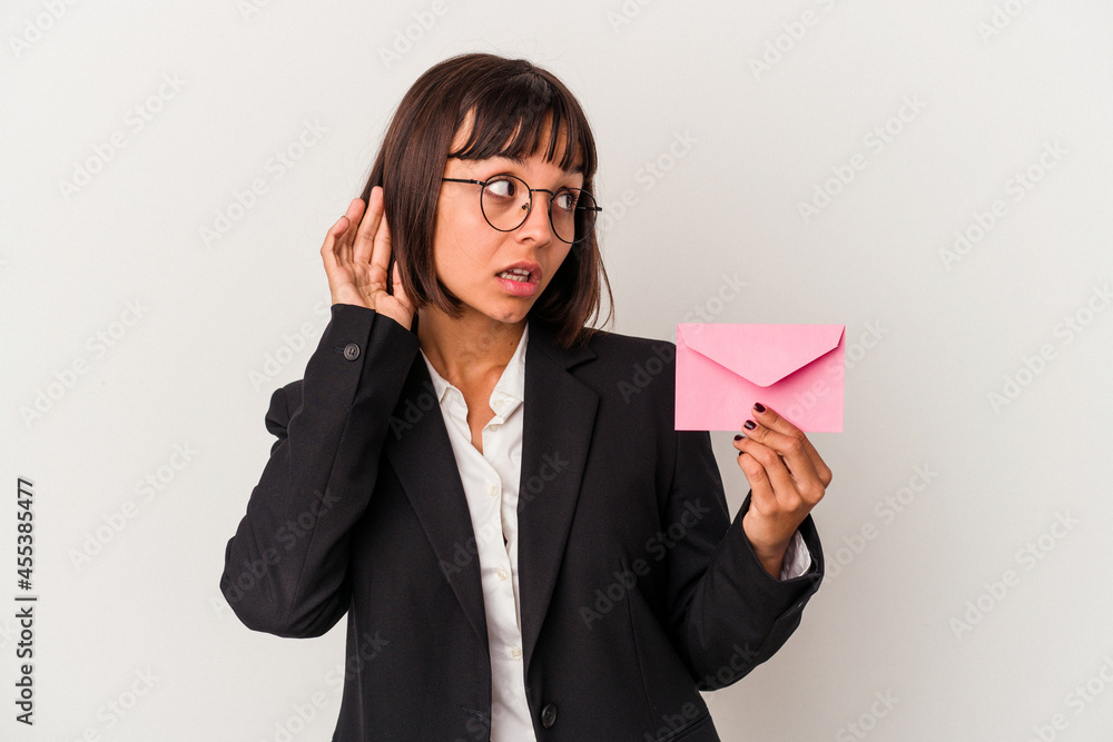 Young mixed race business woman holding a letter isolated on white background trying to listening a gossip. Young mixed race business woman holding a letter isolated on white background trying to listening a gossip.
