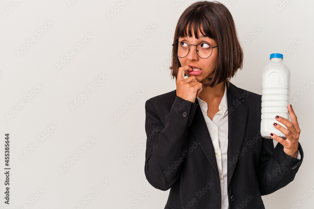 Young mixed race business woman holding a milk bottle isolated on white background relaxed thinking about something looking at a copy space. Young mixed race business woman holding a milk bottle isolated on white background relaxed thinking about something looking at a copy space.