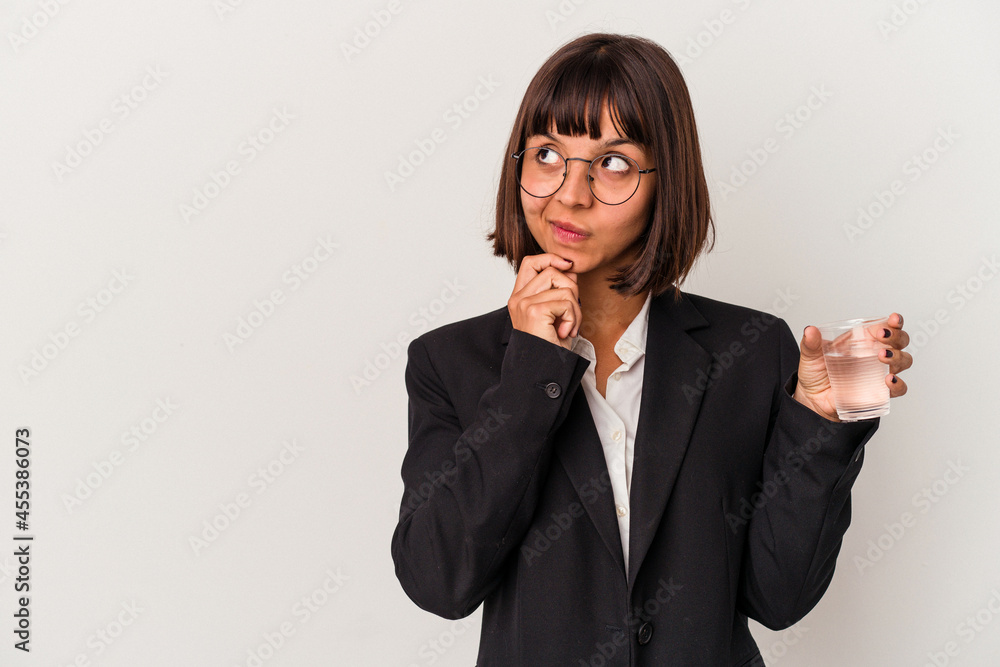 Young mixed race business woman holding a glass of water isolated on white background looking sideways with doubtful and skeptical expression. Young mixed race business woman holding a glass of water isolated on white background looking sideways with doubtful and skeptical expression.