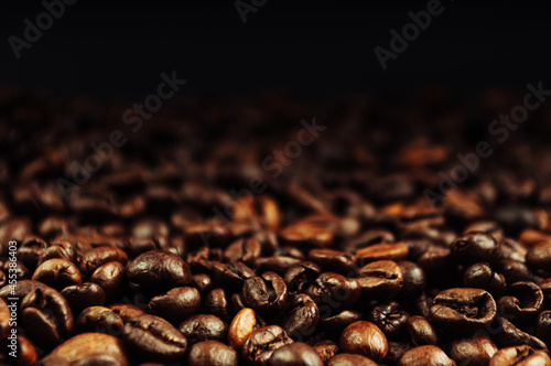 Coffee beans close up. The concept of making aromatic strong coffee on a black background in a low key. Discreet photography.