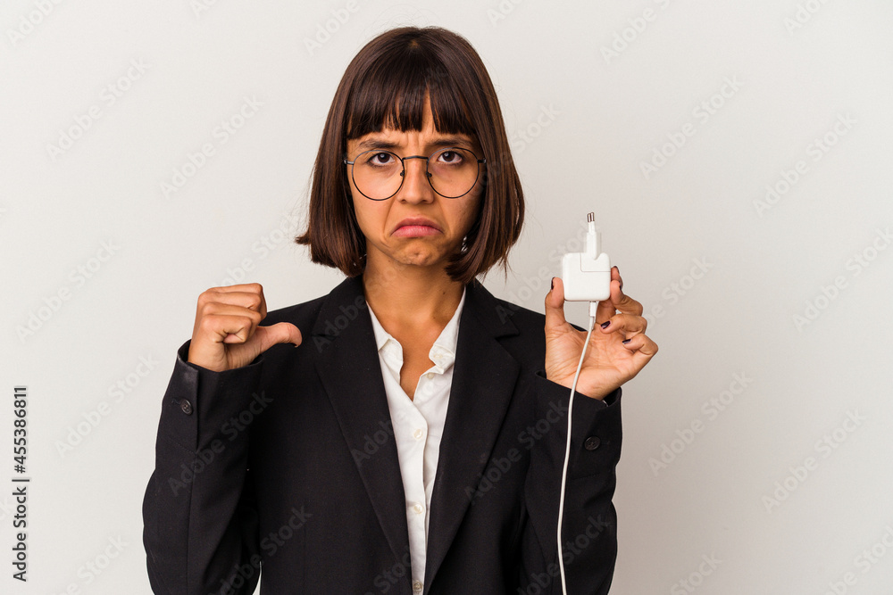 Young mixed race business woman holding a phone charger isolated on white background points with thumb finger away, laughing and carefree. Young mixed race business woman holding a phone charger isolated on white background points with thumb finger away, laughing and carefree.