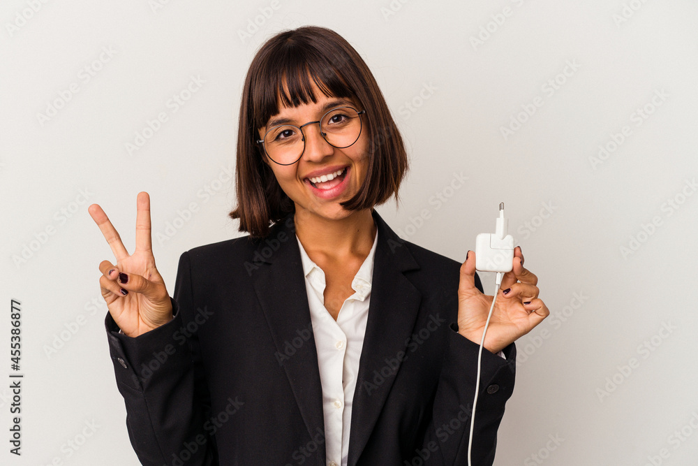 Young mixed race business woman holding a phone charger isolated on white background cheerful and confident showing ok gesture. Young mixed race business woman holding a phone charger isolated on white background cheerful and confident showing ok gesture.