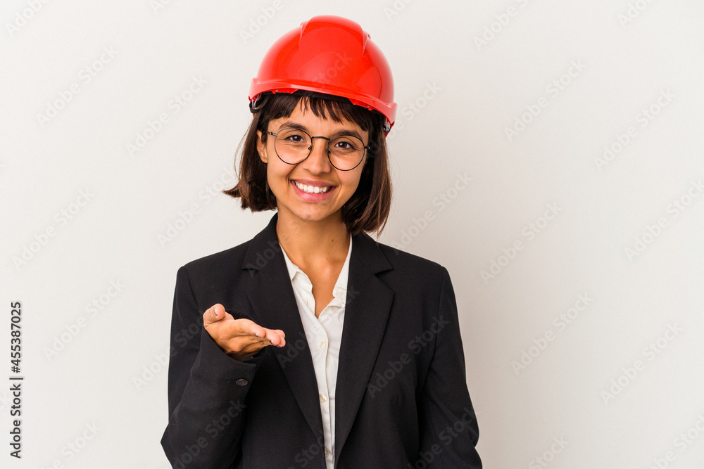 Young architect woman with red helmet isolated on white background stretching hand at camera in greeting gesture. Young architect woman with red helmet isolated on white background stretching hand at camera in greeting gesture.