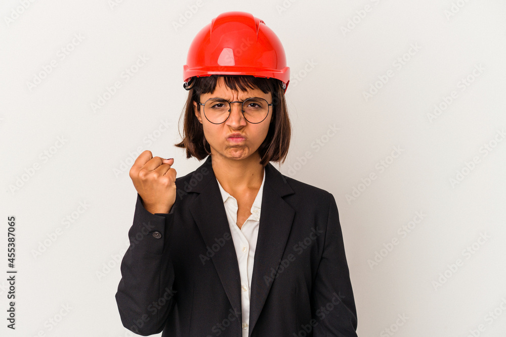 Young architect woman with red helmet isolated on white background showing fist to camera, aggressive facial expression. Young architect woman with red helmet isolated on white background showing fist to camera, aggressive facial expression.
