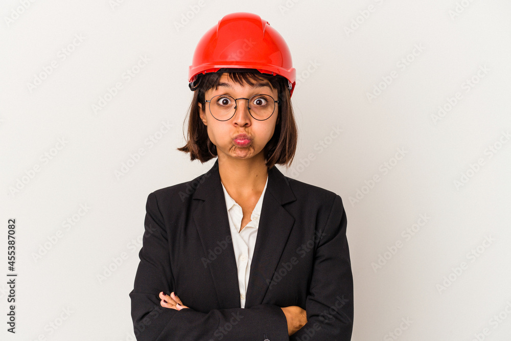 Young architect woman with red helmet isolated on white background blows cheeks, has tired expression. Facial expression concept. Young architect woman with red helmet isolated on white background blows cheeks, has tired expression. Facial expression concept.