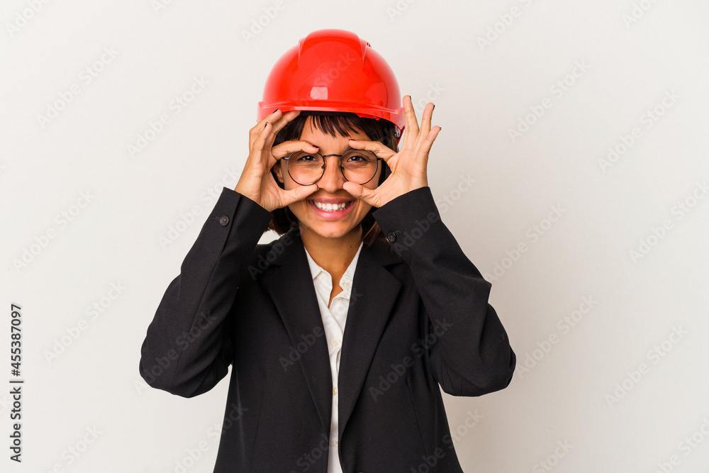 Young architect woman with red helmet isolated on white background showing okay sign over eyes Young architect woman with red helmet isolated on white background showing okay sign over eyes